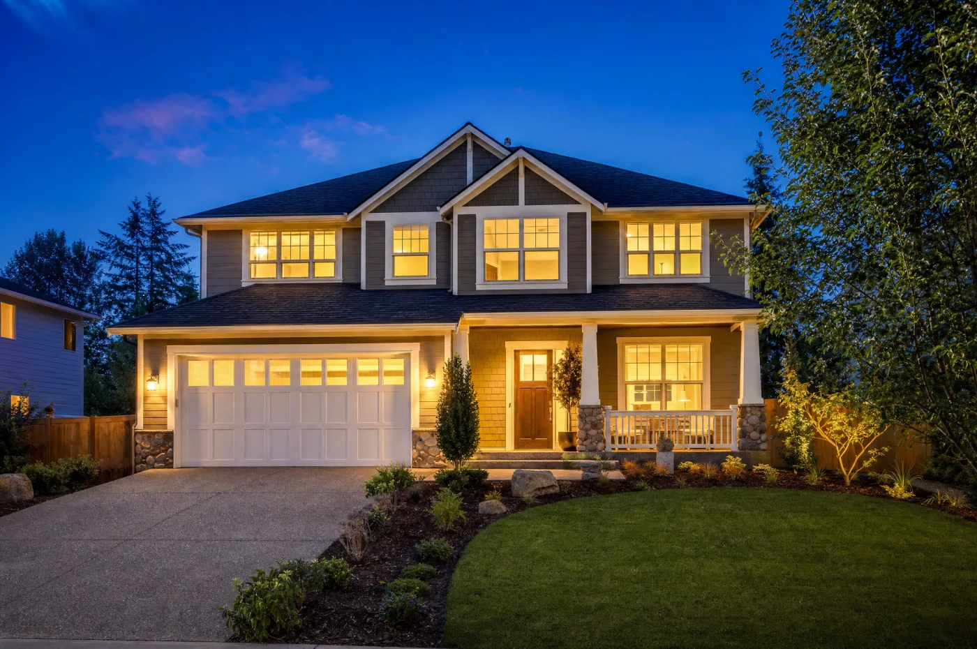 Twilight real estate exterior photo, warm window light against a deep blue dusk sky, HDR quality